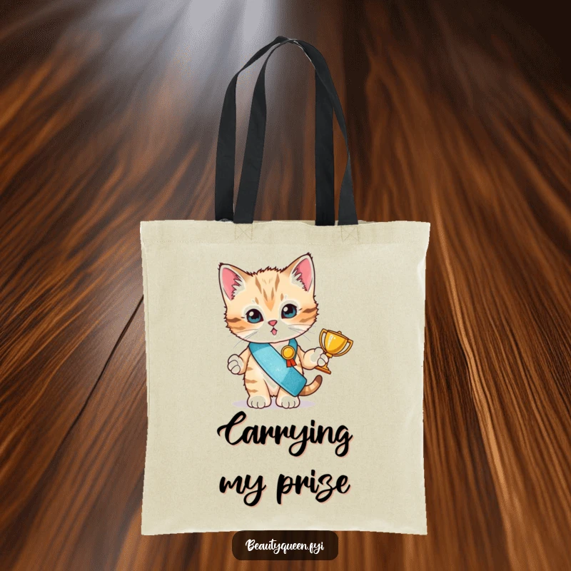 Funny tote bag with a tiny kitten in a glitter sash proudly holding a small trophy, designed for a champion.